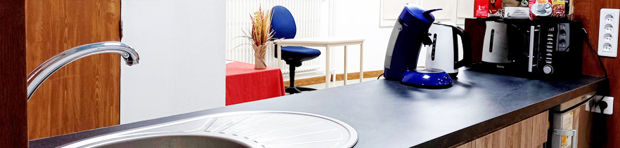 Ilot central avec machine à café, bouilloire, frigo, micro-onde dans l'une des salles en location à Belfort